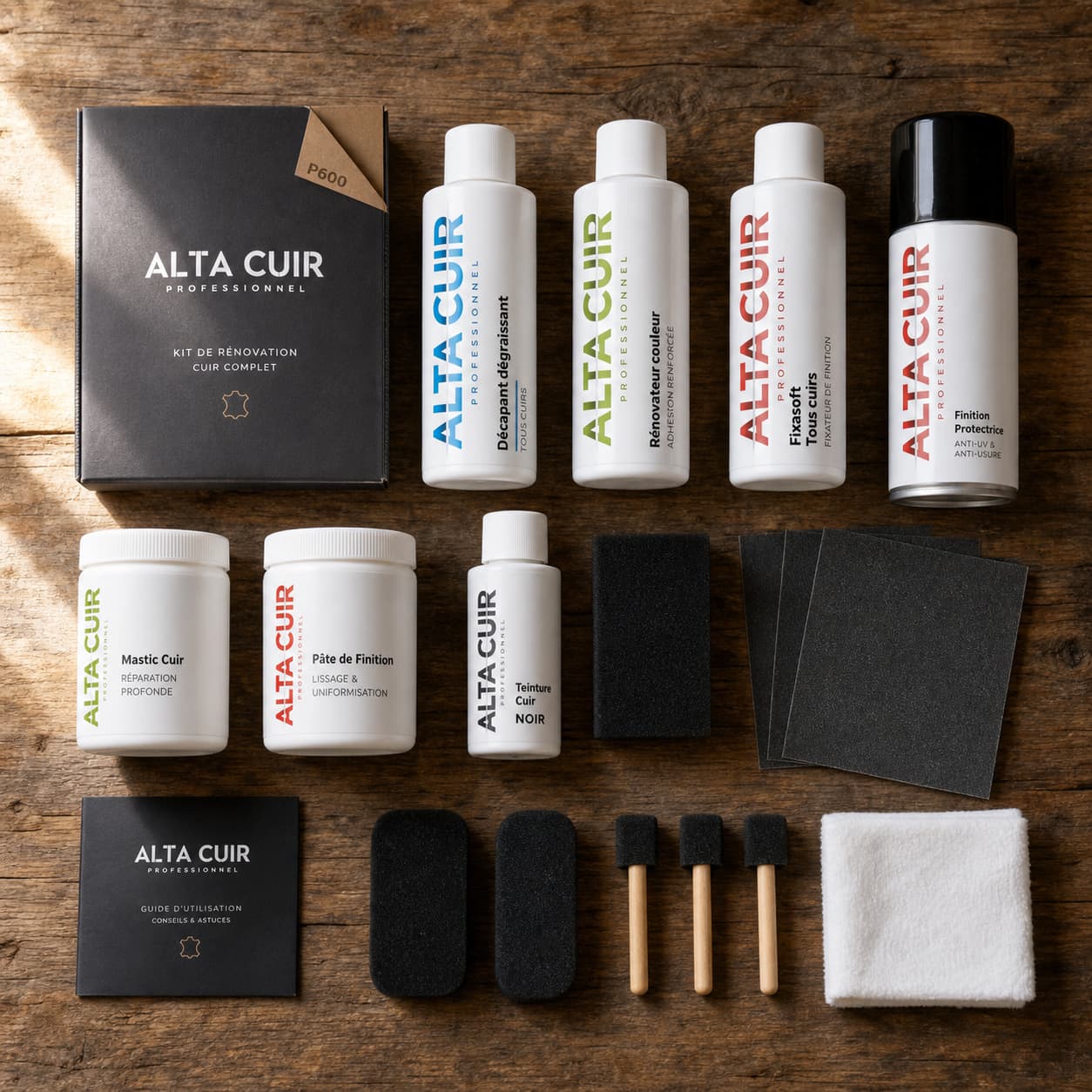 Un kit de rénovation du cuir Alta Cuir disposé à plat sur une table en bois rustique, comprenant des bouteilles de nettoyant, de mastic, de teinture et des éponges, avec un éclairage naturel latéral créant des ombres douces et le logo Alta Cuir visible sur l